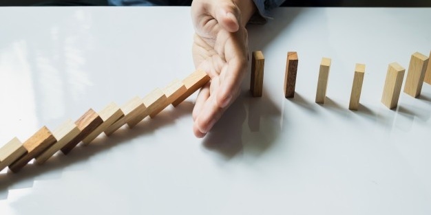 mao-de-empresario-para-domino-continuamente-derrubado-ou-risco-com-copyspace_1423-15